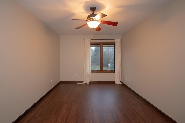 unfurnished room with a ceiling fan, baseboards, and dark wood-style flooring