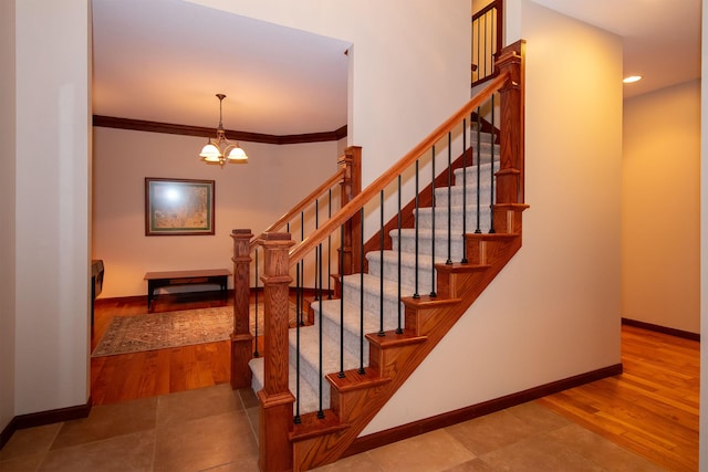 staircase featuring baseboards, a chandelier, and ornamental molding