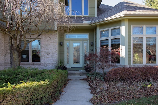 property entrance featuring brick siding and roof with shingles