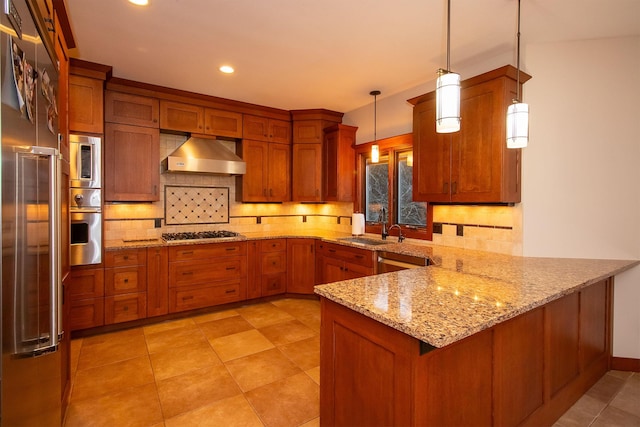 kitchen with under cabinet range hood, brown cabinets, appliances with stainless steel finishes, and a peninsula