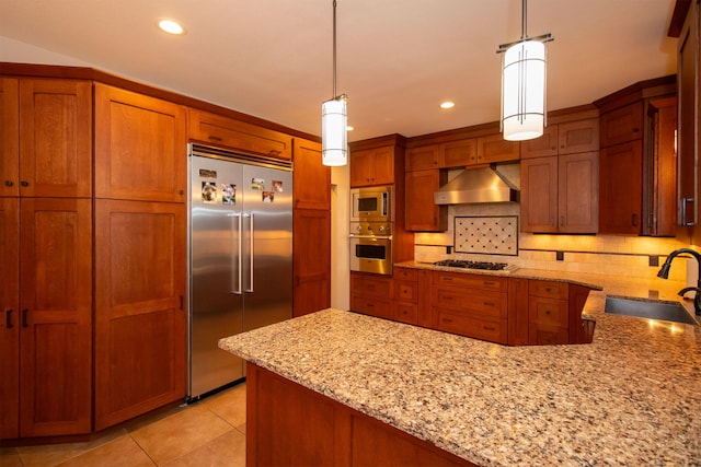 kitchen featuring under cabinet range hood, built in appliances, brown cabinetry, and a sink