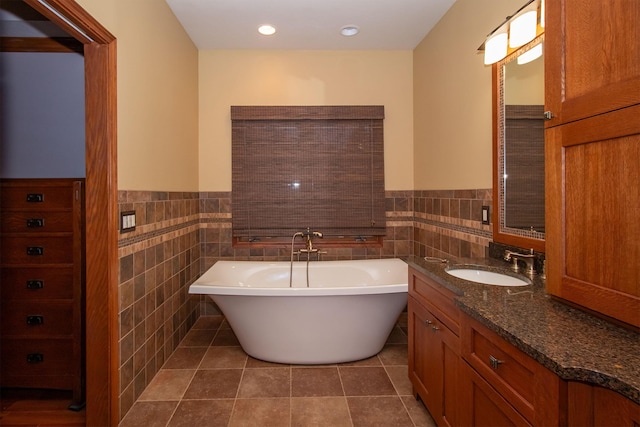 bathroom with tile patterned flooring, a soaking tub, wainscoting, and tile walls