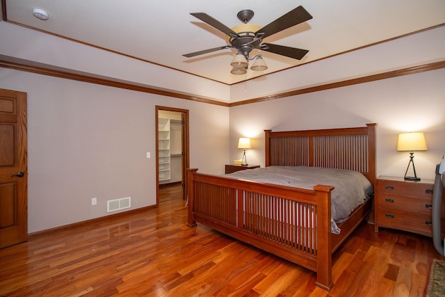 bedroom with visible vents, crown molding, a ceiling fan, and wood finished floors