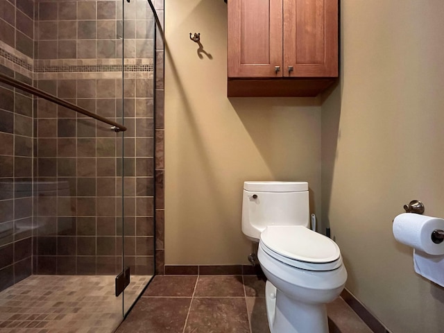 full bath with toilet, tiled shower, and baseboards