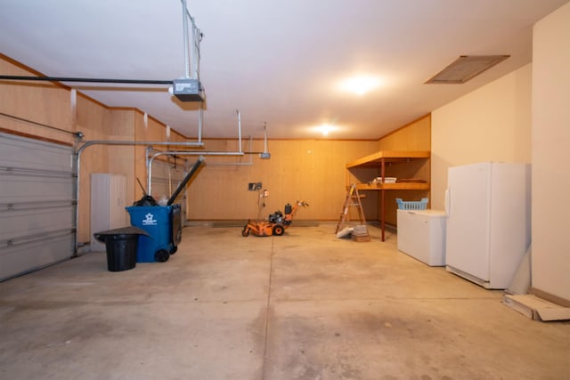 garage with a garage door opener, wood walls, and freestanding refrigerator