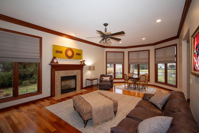 living area featuring wood finished floors, a ceiling fan, a fireplace, recessed lighting, and ornamental molding