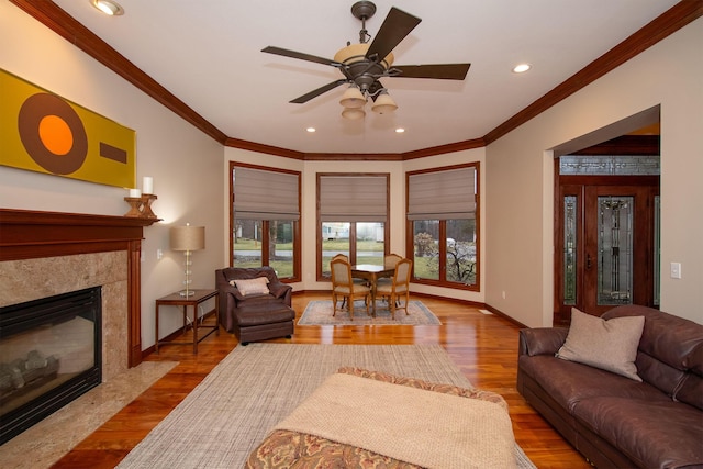 living area featuring a fireplace, crown molding, baseboards, and wood finished floors