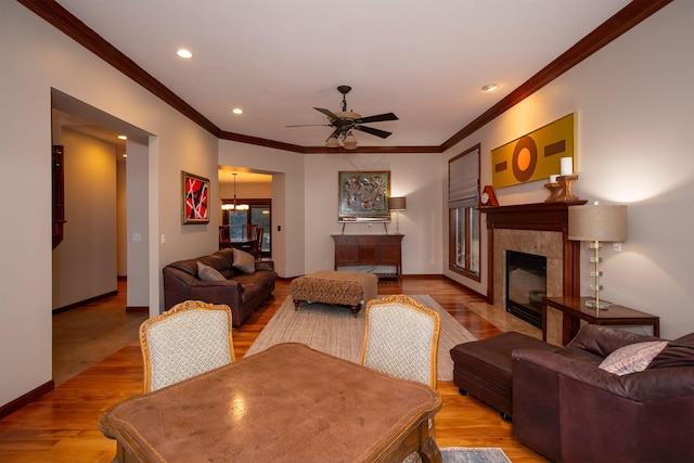 living room with crown molding, wood finished floors, baseboards, and a tile fireplace