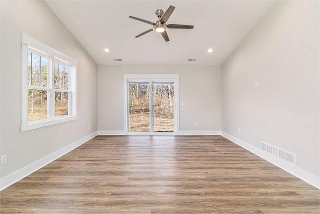 empty room with light wood-type flooring, visible vents, lofted ceiling, and baseboards