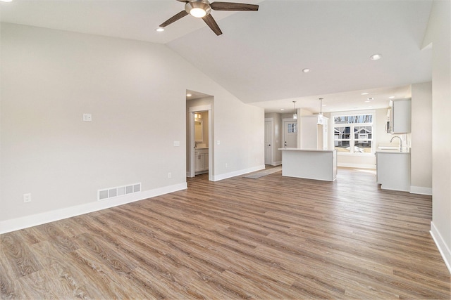 unfurnished living room featuring lofted ceiling, wood finished floors, visible vents, and baseboards