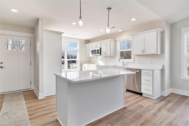 kitchen with light countertops, light wood-style floors, white cabinets, stainless steel appliances, and a sink