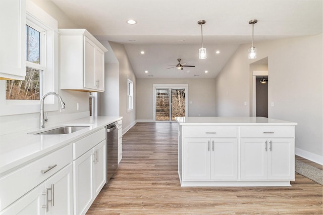 kitchen featuring white cabinetry, a sink, pendant lighting, stainless steel dishwasher, and light wood-type flooring