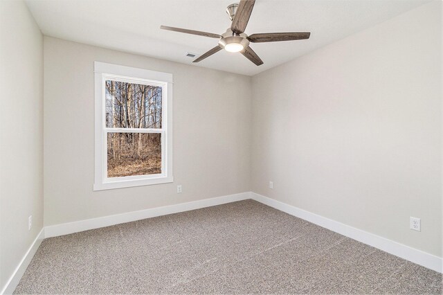 carpeted spare room with visible vents, baseboards, and ceiling fan