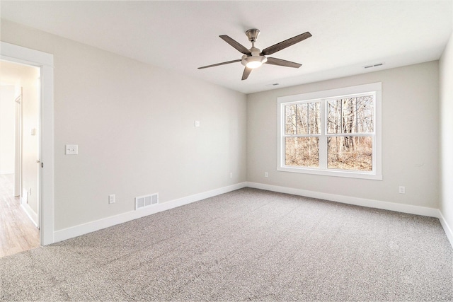 carpeted spare room featuring visible vents, ceiling fan, and baseboards