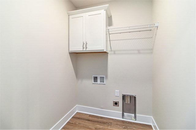 clothes washing area featuring baseboards, hookup for a washing machine, wood finished floors, cabinet space, and hookup for an electric dryer