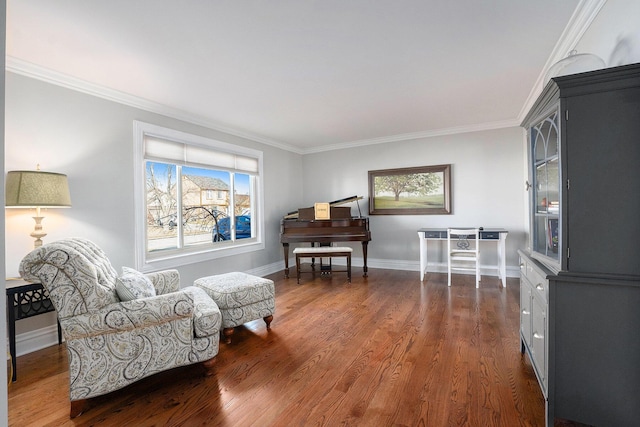 sitting room with dark wood-type flooring, crown molding, and baseboards