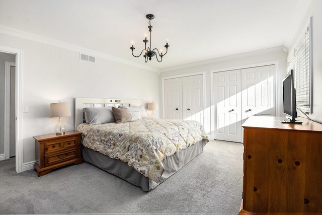 carpeted bedroom with a notable chandelier, ornamental molding, visible vents, and multiple closets