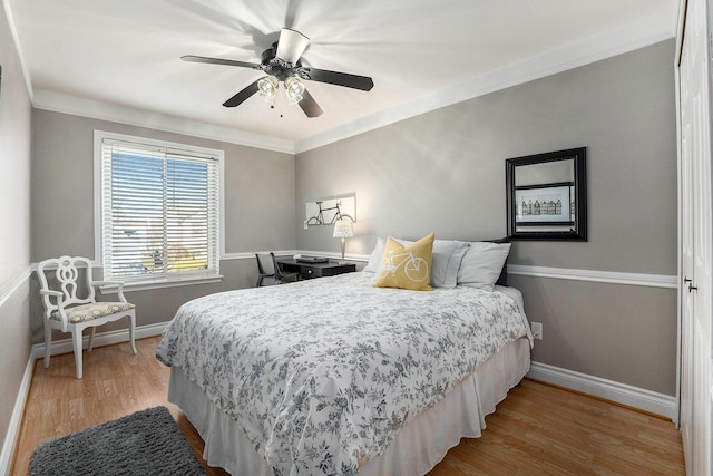 bedroom featuring a ceiling fan, crown molding, wood finished floors, and baseboards