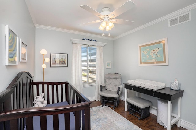 bedroom with visible vents, crown molding, baseboards, dark wood finished floors, and a nursery area