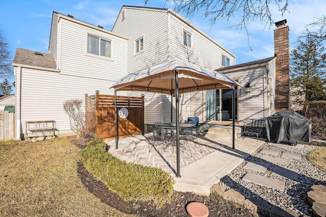 rear view of property featuring a gazebo, a chimney, a patio, and fence