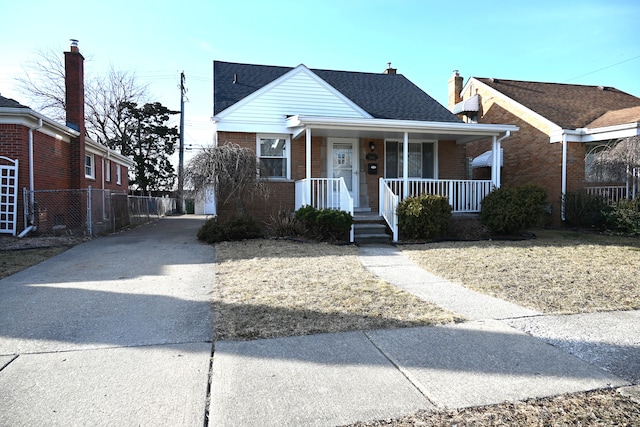 bungalow-style home featuring brick siding, covered porch, and a shingled roof