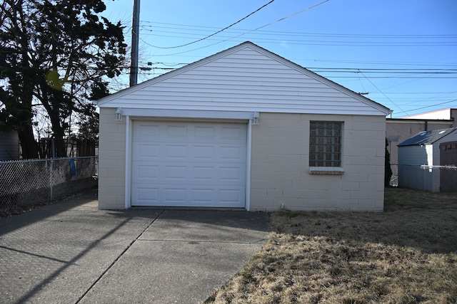 detached garage featuring fence and driveway