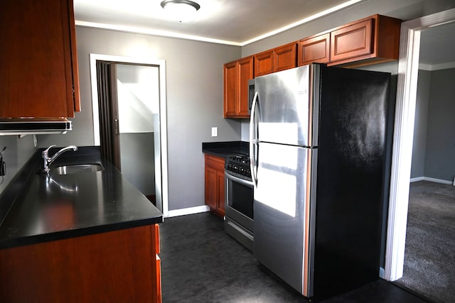 kitchen featuring dark countertops, baseboards, appliances with stainless steel finishes, and a sink