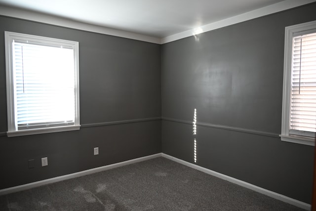 unfurnished room featuring baseboards and dark carpet