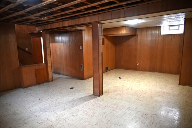 basement featuring tile patterned floors and wood walls