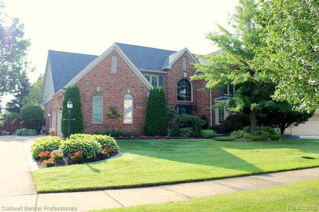 view of front of home featuring brick siding, a garage, driveway, and a front lawn