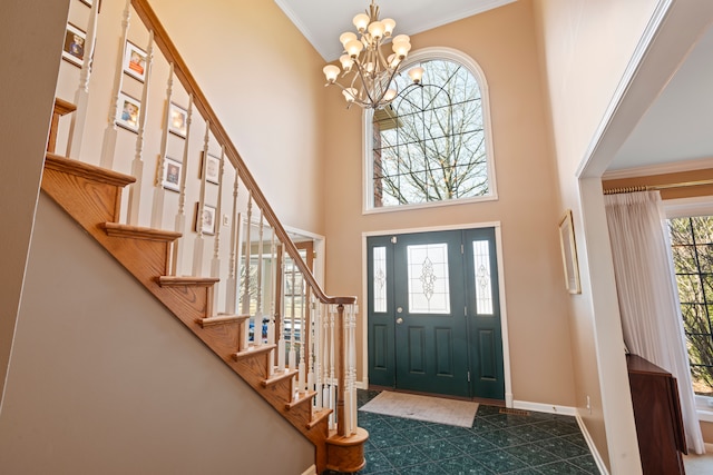 foyer entrance featuring crown molding, baseboards, stairs, a high ceiling, and an inviting chandelier