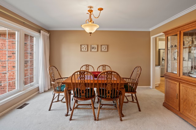 dining space featuring visible vents, light colored carpet, baseboards, and ornamental molding