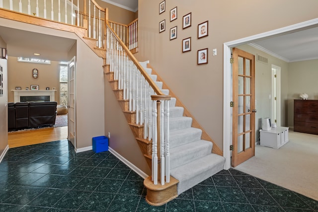 stairs featuring visible vents, a fireplace, baseboards, and ornamental molding