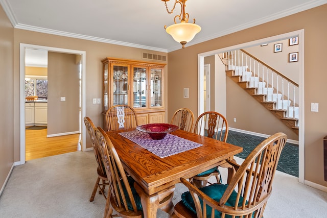 dining space with visible vents, crown molding, baseboards, stairs, and light carpet