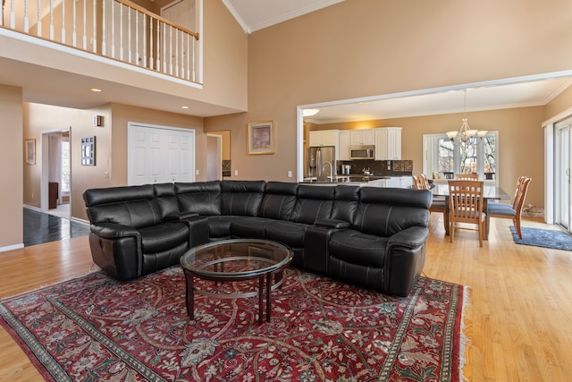 living area with an inviting chandelier, light wood-style flooring, and crown molding