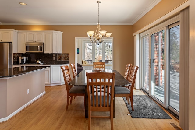 dining space with visible vents, a chandelier, light wood-style flooring, and ornamental molding