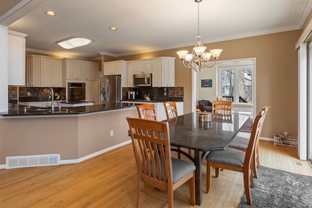 dining area featuring visible vents, light wood finished floors, recessed lighting, crown molding, and a notable chandelier