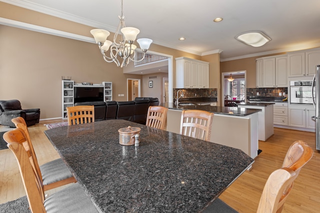 dining room with light wood finished floors, a notable chandelier, recessed lighting, and crown molding