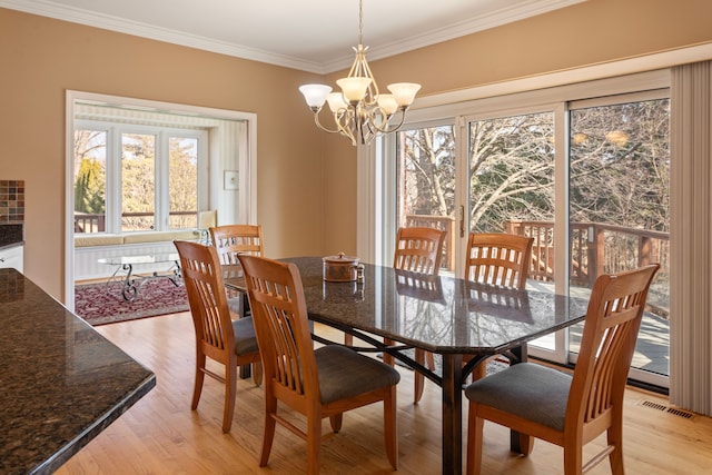 dining room with visible vents, a notable chandelier, ornamental molding, and light wood finished floors