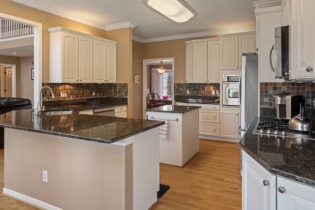 kitchen featuring a sink, light wood-style floors, appliances with stainless steel finishes, a peninsula, and crown molding