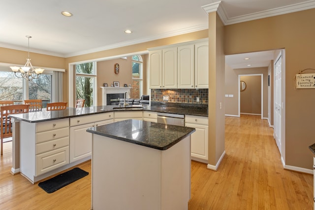 kitchen featuring a sink, ornamental molding, a peninsula, and stainless steel dishwasher