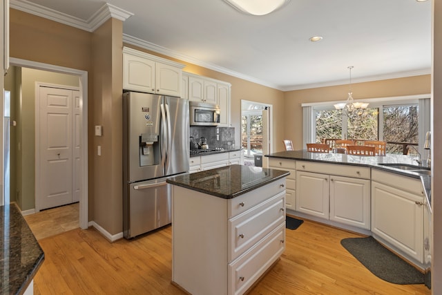 kitchen with a sink, stainless steel appliances, light wood-style floors, crown molding, and a chandelier