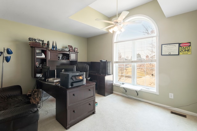 office featuring light colored carpet, a ceiling fan, visible vents, and baseboards