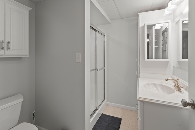 bathroom with vanity, a shower stall, toilet, and baseboards