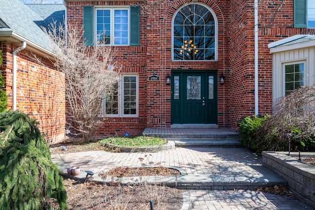 property entrance featuring brick siding and roof with shingles