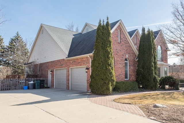 view of side of home with brick siding, fence, concrete driveway, roof with shingles, and an attached garage