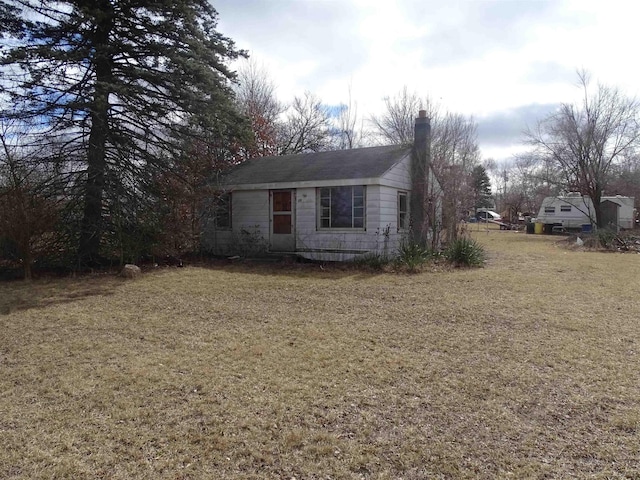 view of front of house with a chimney and a front lawn