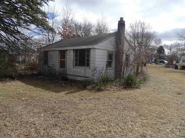 view of side of home featuring a lawn and a chimney