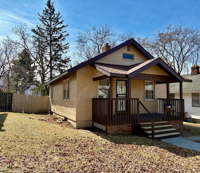 bungalow-style house featuring fence, roof with shingles, and a chimney