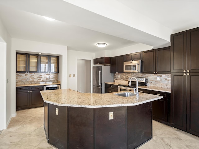 kitchen featuring a sink, stainless steel appliances, dark brown cabinetry, glass insert cabinets, and backsplash